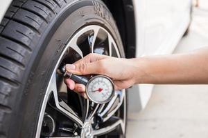 Close-Up Of Hand holding pressure gauge for car tyre pressure measurement photo