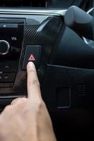 Closeup of young woman pressing emergency button on car sport dashboard. photo