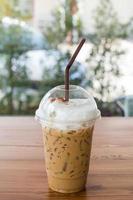 Iced coffee in plastic glass on wooden table. Selective focus. photo