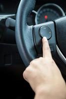 A woman hand pushes the volume control button on a steering wheel. photo