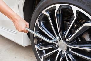 Hands disassembling a modern car wheel steel rim with a lug wrench for change wheel photo