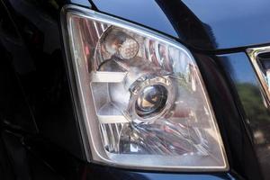 Closeup headlights of modern black car with projector lens photo