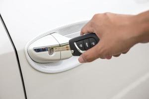 Closeup of a woman's hand inserting a key into the door lock of a white car photo