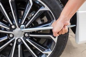 Hands disassembling a modern car wheel steel rim with a lug wrench for change wheel photo