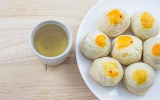 Chinese Pastry Mung Bean or Mooncake with Egg Yolk on dish wooden table and green tea cup photo