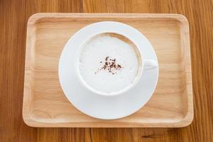 cappuccino in a white cup on a wooden plate on table photo