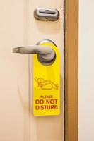 Please do not disturb sign hang on door knob in hotel photo