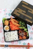 Top View Japanese Bento Lunchbox with Vegetable, Nugget, Sausage, Edamame, and Tempura photo