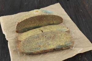 green mildew on a stale bread. Surface of moldy bread. Spoiled bread with mold. Moldy fungus on rotten bread. photo