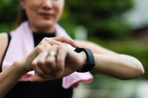 Unrecognizable sporty women in sports wear raise hand and use finger to adjust setting application in smartwatch on wrist to checking result after workout or exercise. Concept of good health care photo