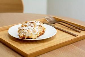 Desert and sweet bakery concept. Close up croissant almond on a white plate in cafe and coffee shop. photo