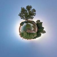 Little planet transformation of spherical panorama 360 degrees. Spherical abstract aerial view near river with awesome beautiful clouds. Curvature of space. photo