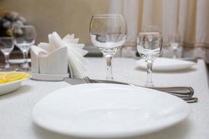 banquet table served with instruments and decorated with empty wine glasses photo