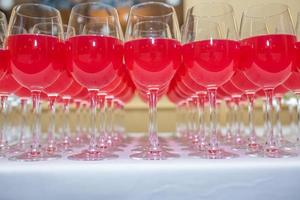 lot of blurred glasses with red wine on the reception party table on light background photo