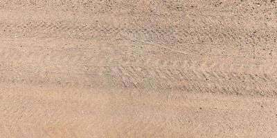 view from above on surface of gravel road with car tire tracks photo