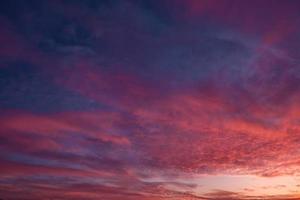 Blue violet red sunset sky background with evening fluffy curly rolling cirrostratus clouds. Good windy weather photo