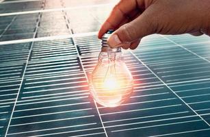 hand holding lightbulb on solar panel concept clean energy in nature photo