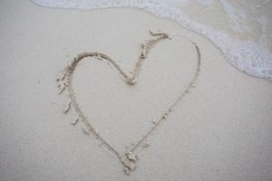 corazones dibujados en la arena de una playa foto