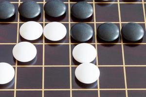 gameplay of Go game on wooden board close up photo