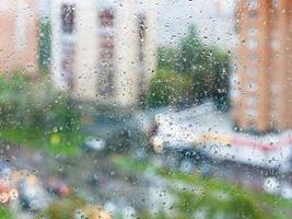 raindrops on home window glass and blurred street photo