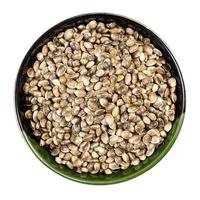 unpeeled hemp seeds in round bowl isolated photo