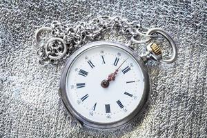 antique pocket watch on silver fabric background photo