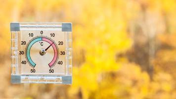 thermometer on window and blurred yellow forest photo