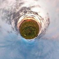 Little planet transformation of spherical panorama 360 degrees. Spherical abstract aerial view in field in nice evening with awesome beautiful clouds. Curvature of space. photo