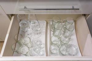 lot of empty glasses on the shelf in the kitchen cupboard photo