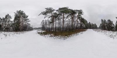 Winter full spherical hdri panorama 360 degrees angle view road in a snowy pinery forest with gray pale sky in equirectangular projection. VR AR content photo