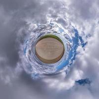 Little planet transformation of spherical panorama 360 degrees. Spherical abstract aerial view in field with awesome beautiful clouds. Curvature of space. photo