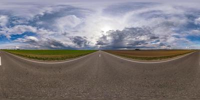 vista de ángulo de 360 grados de panorama hdri esférico completo sin tráfico en carretera asfaltada entre campos por la noche antes de la puesta del sol con cielo nublado. Panorama 360 en proyección equirrectangular, contenido vr ar foto