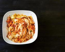above view of kimchi in bowl on dark wooden board photo