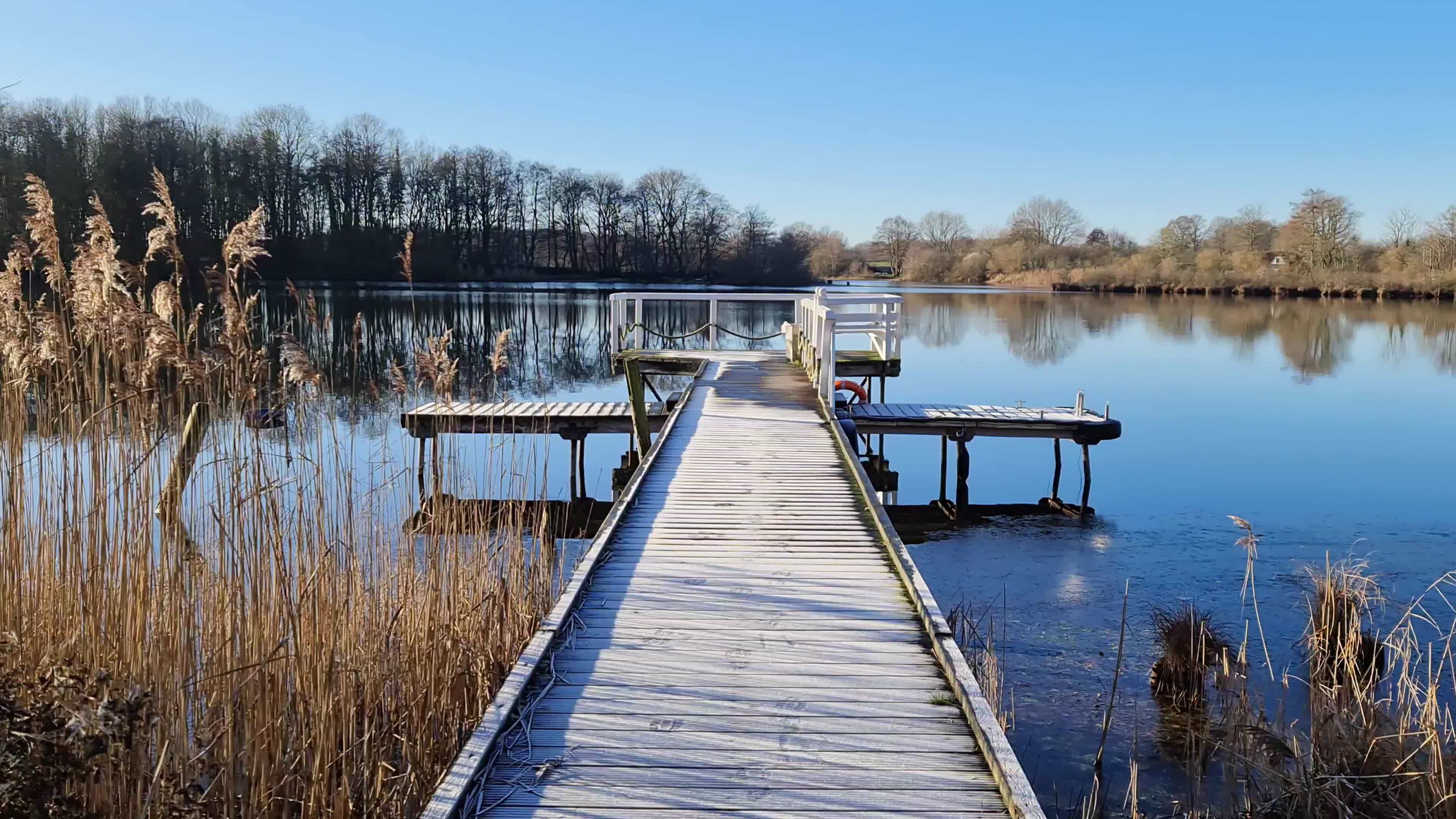 Beautiful landscape while walking on a jetty by a lake with blue sky ...