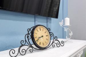 old vintage clock on a fireplace shelf in a rich interior with a candlestick photo