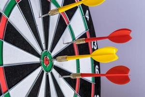 Red and yellow dart arrows hitting in the target center of dartboard. Success hitting target aim goal achievement concept photo