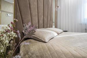 interior de la habitación de lujo moderna con almohadas en la cama en apartamentos tipo estudio en estilo de color claro foto