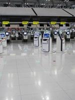 Self check in machine hall and help desk kiosk at airport for check in, printing boarding pass or buying ticket, Bangkok International Airport, Thailand photo