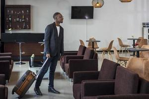 hombre de negocios afroamericano vestido formalmente con equipaje está abordando el avión desde la sala de embarque del aeropuerto