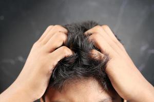 teenage boy Scratching Head Against black background . photo