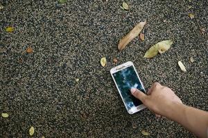 los hombres recogen a mano un teléfono inteligente roto del piso foto