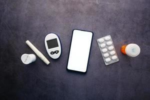 Teléfono inteligente y herramientas de medición para diabéticos y píldoras en la mesa foto