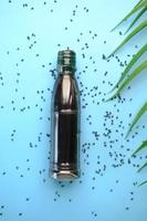 Black Cumin seeds and oils in a container on blue background photo