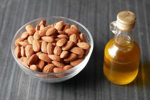 nueces de almendras en un bol y aceite en un frasco sobre la mesa foto