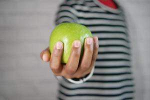 hand holding green apple on black background photo