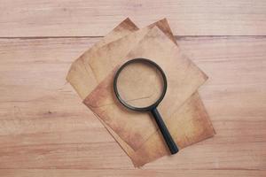 empty old paper and magnifying glass on table. photo