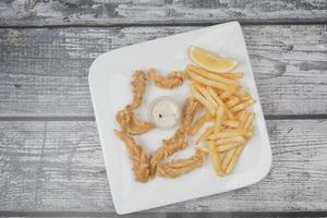 Crunchy Deep fried squid stick and french fries on table photo