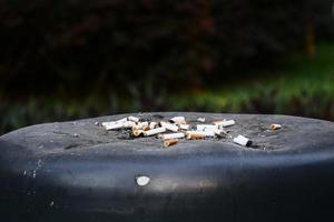 Close up burning cigarette in ashtray on waste bin photo