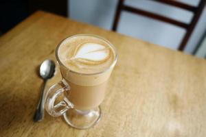 a cup of late coffee with flower shape design on top at cafe photo