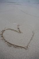 corazones dibujados en la arena de una playa foto